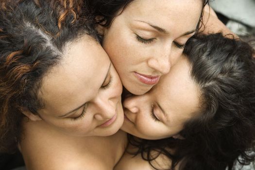 Three nude brunette Caucasian mid-adult women embracing each other with eyes closed.