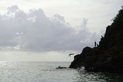 Jumping off a rock into the ocean, silhouette.