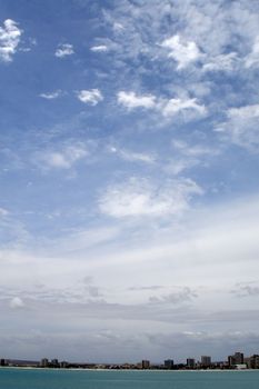 A cityscape with the ocean and a lot of sky.