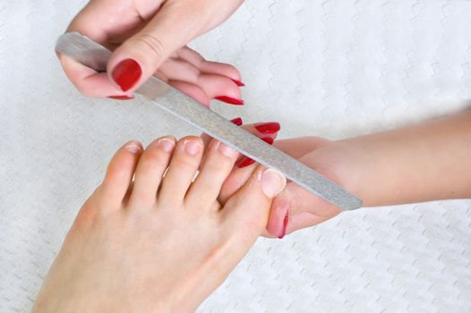 applying pedicure, acting with toenails using nail file