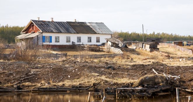 The old shabby rural wooden house with an outhouse