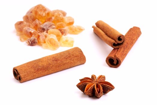 Star anise, three cinnamon sticks and brown sugar on a white background