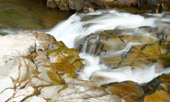 Falling water - Small waterfall at morning river in mountains