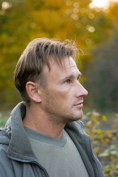The young man in a grey jacket against the autumn nature