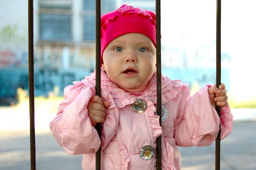 Pretty little girl behind old railing (grille).