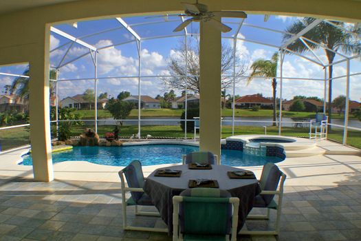 A view from a lanai of a pool, spa and lake.