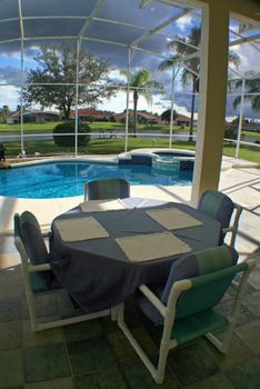 A view from a lanai of a pool, spa and lake.