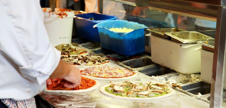 Different Pizza Being Made in a Kitchen