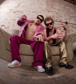 Two very expressive party goers sitting on a sofa