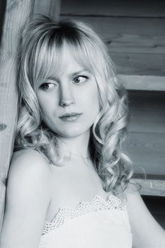 The blond girl in a white dress near a wooden ladder