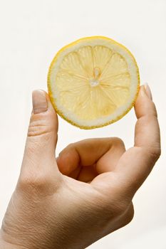 Woman hand holding up a wedge of lemon, isolated on white