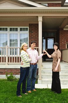 Happy couple getting keys to new house from real estate agent