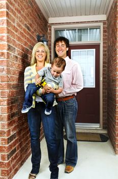 Young happy family in front of house