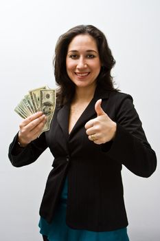 Smiling business woman holding up fanned money and a thumb up, isolated on white