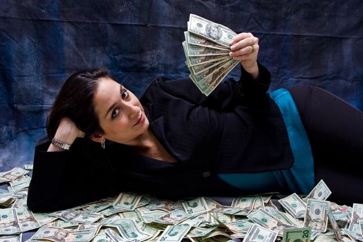 Rich business woman waving money and laying with her money isolated on a dark background