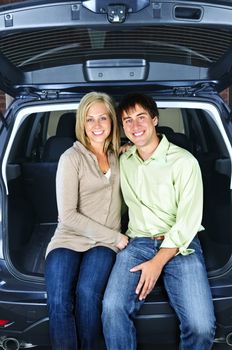 Happy young couple sitting at back of car