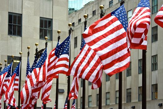 Wind is blowing through a row of American flags at the Rockefeller Center in New York City