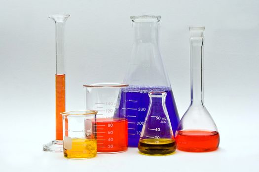 Flasks, cylinders and beakers with colorful liquids as pH indicators on a white background