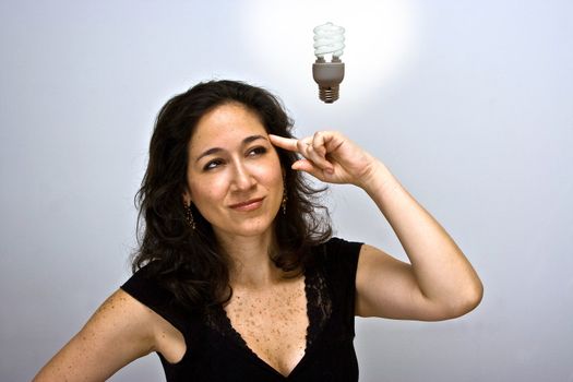 Woman who just came up with a great environmentally friendly idea. Pointing up her finger at her head and having a fluorescent idea bulb hanging above her head