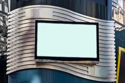 A LCD TV on a building for advertisement; used as a billboard; frame with black border; on a silver colored waved background.