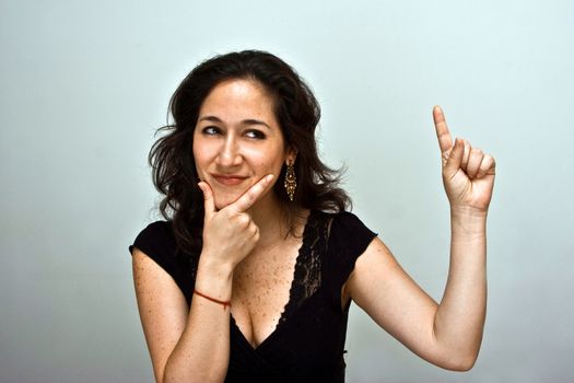 Woman thinking about a new idea, pointing finger in the air and having her hand on her chin