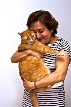 An older lady in a black and white striped shirt holding an orange cat.