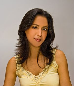 Beautiful face of a young dark brown haired latina woman wearing a yellow shirt and glossy deep red lips and gold eyeshadow, isolated on white