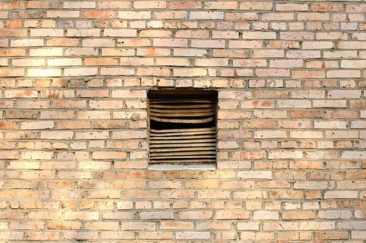 Old metal rusty ventilation window on brick wall.