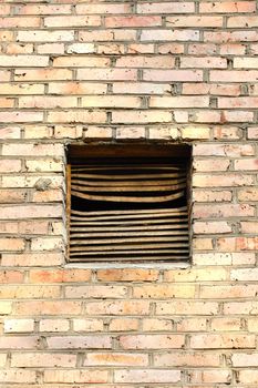 Old metal rusty ventilation window on brick wall.