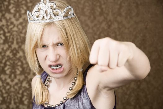 Portrait of pretty young girl wearing tiara throwing a punch