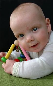 Baby (3 months old) playing happily with a colorful rattle