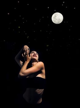 Artistic portrait of young woman posing under starry night with full moon