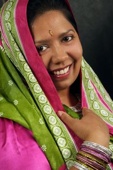 A beautiful Indian woman wearing a traditional sari and smiling.
