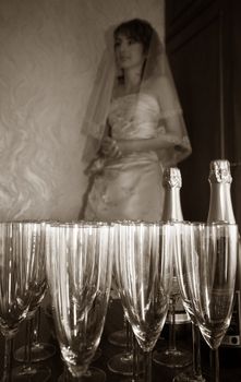 The worrying bride pending the groom on a background of glasses