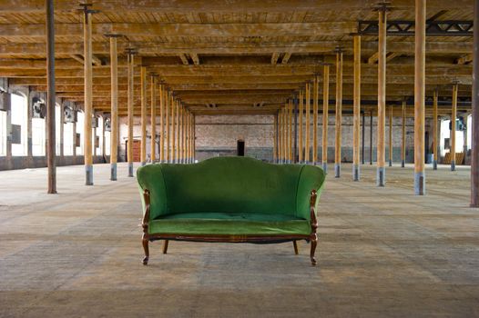 Image of an antique green couch in old, loft style building with wooden columns