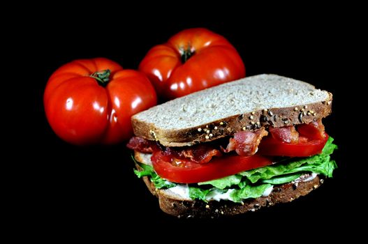 Bacon, lettuce, and tomato sandwich with tomatoes.  Isolated on black background.