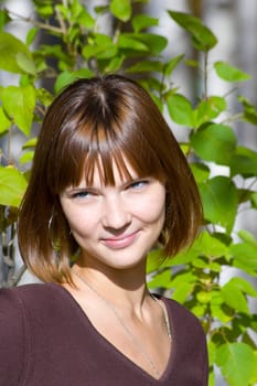 Portrait of the beautiful young girl against green foliage