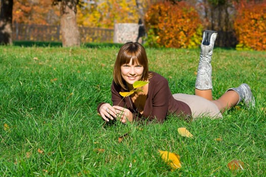 The young girl on a green grass in autumn park