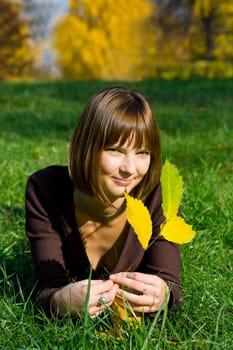 The young girl on green grass in autumn park