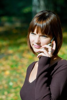 The young girl talks by a mobile phone. Outdoor
