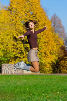 The nice jumping girl against the autumn nature