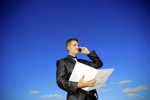 Young man holding a folder while talking on the phone.