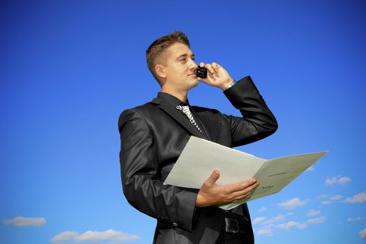 Young man holding a folder while talking on the phone.