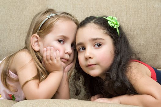 two cute little girls lying on the sofa