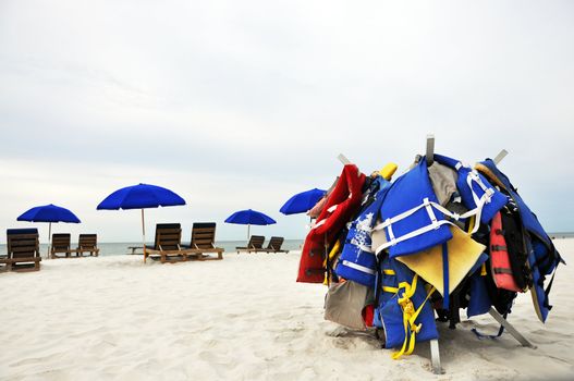 Beach umbrellas, chairs, and life jackets on deserted beach.