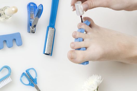 putting red varnish on foot nails with acessory in background