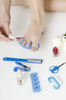 putting red varnish on foot nails with acessory in background