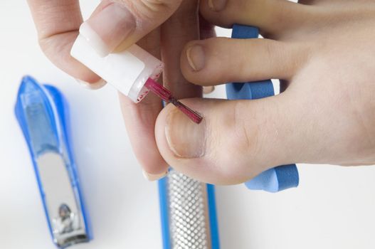 putting red varnish on foot nails with acessory in background