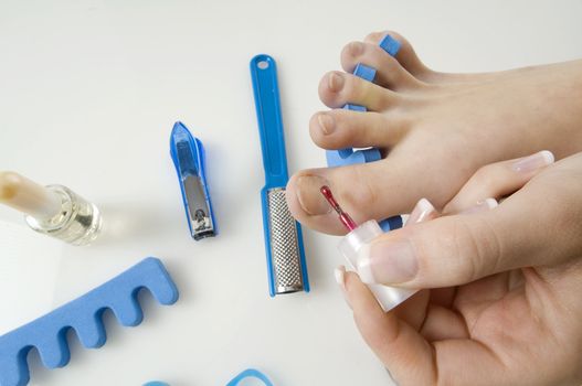 putting red varnish on foot nails with acessory in background