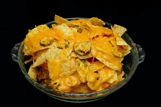 Plate of nachos with jalapeno peppers.  Isolated on black background.